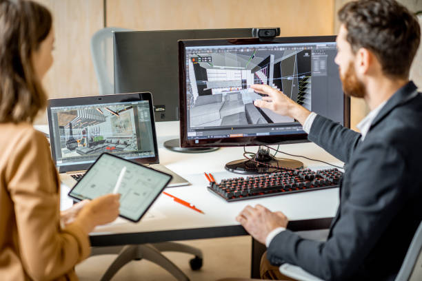 Two creative office employees making interior design on the computer and digital tablet at the modern office of architectural firm. Concept of 3d modeling and digital Interior designing